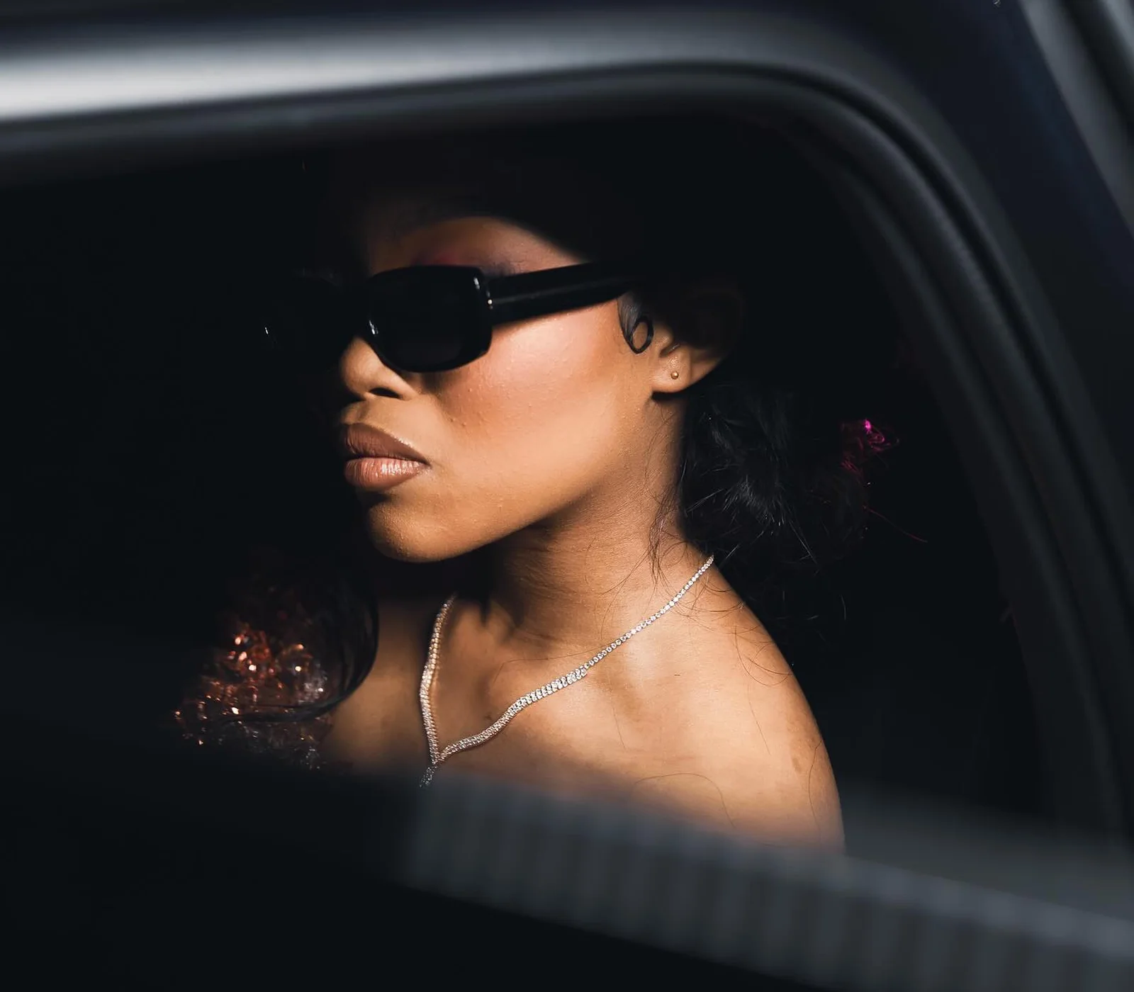 A matric dance portrait shot through the open window of a car at night, dramatic side light